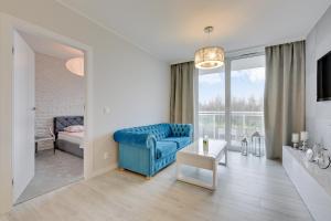 ein Wohnzimmer mit einem blauen Stuhl und einem Sofa in der Unterkunft Apartament Mistral Gdynia in Gdynia