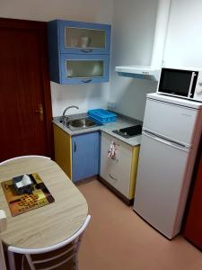 a small kitchen with a white refrigerator and a table at Apartamento Study 1 Select Real Caldas de Reis in Caldas de Reis