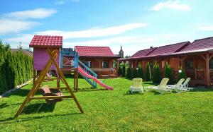 a playground with a slide and chairs in a yard at AMANDA Domki letniskowe in Darłowo