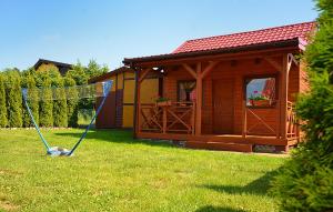 a swing in front of a cabin in a yard at AMANDA Domki letniskowe in Darłowo +2 photos