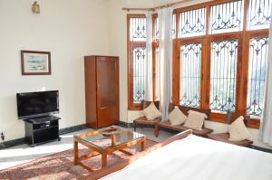 a living room with a couch and a tv and windows at Sandy's Homestay in Jammu