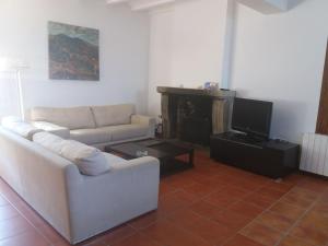 a living room with a couch and a tv at Casa Rural de Benjamin Palencia in Villafranca de la Sierra