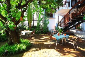 a patio with a table and chairs under a tree at iuDia Hotel in Phra Nakhon Si Ayutthaya