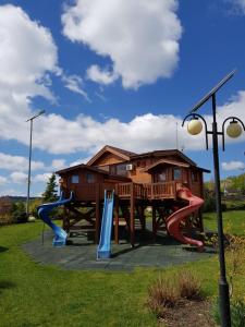 a log cabin with a playground in the yard at Sat de vacanta Ciprian Porumbescu in Suceava