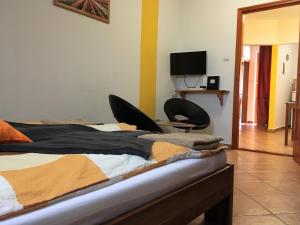 a bedroom with a bed with two chairs and a television at AIDA Apartman in Gyula