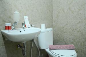 a bathroom with a white toilet and a sink at Minimalist Studio Room at Grand Serpong Apartment By Travelio in Tangerang +11 photos
