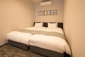 a small bedroom with a bed with white sheets at HOTEL R9 Kujukuri "ex Casual Resort COFF Ichinomiya" in Ichinomiya