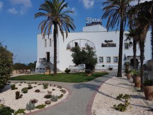 a white building with palm trees in front of it at Relais Sant'Eligio in Ostuni