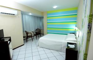 a hotel room with a bed and a striped wall at Hotel Imperial in Mossoró