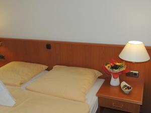 a room with two beds and a table with a lamp at Hotel-Restaurant zum Roeddenberg in Osterode