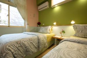 two beds in a room with green walls at Huxi B&B in Ji'an
