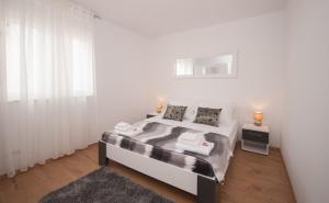 una camera da letto bianca con un letto e una finestra di Apartment Slad a Kaštela (Castelli)