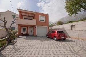 una macchina rossa parcheggiata di fronte a una casa di Apartment Slad a Kaštela (Castelli)