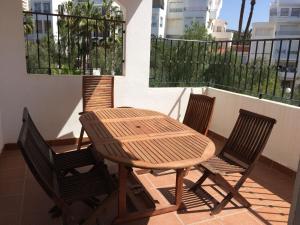 y balcón con mesa de madera y 4 sillas. en Apartamento Elia Villa África, en Aguadulce
