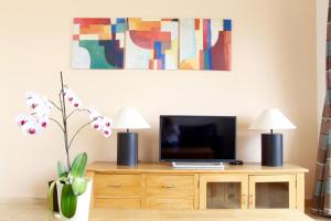 una sala de estar con TV en un armario de madera con 2 lámparas en Melanos Village A21, en Pafos