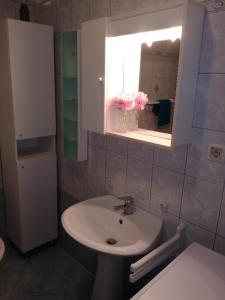 a bathroom with a sink and a window with pink flowers at Apartman Una in Crikvenica