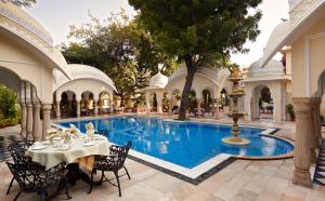 una piscina en un patio con mesa y sillas en Alsisar Haveli - Heritage Hotel, en Jaipur