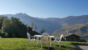three chairs and a table with a view of mountains at alpes studio in Feissons-sur-Salins