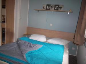 a bed with a blue comforter in a room at Les dunes de contis- landes in Saint-Julien-en-Born