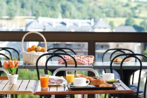 a table with breakfast food and drinks on a balcony at Hotel La Gazelle in Besse-et-Saint-Anastaise