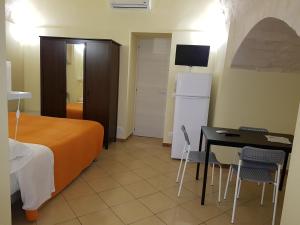 a room with a bed and a table and a refrigerator at Beda Ragusa in Ragusa