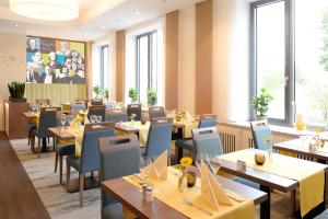 a restaurant with tables and chairs and windows at Ringhotel Loew's Merkur in Nürnberg