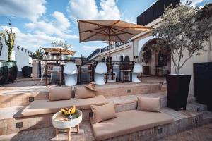 um pátio com sofás, uma mesa e um guarda-chuva em Ambre Epices Medina Riad em Marrakech