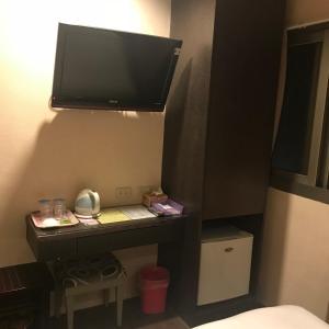 a room with a desk with a television on the wall at Baseball Hotel in Hsinchu City