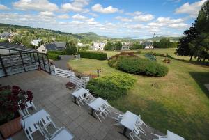 a group of white chairs sitting on a patio at Hotel La Gazelle in Besse-et-Saint-Anastaise