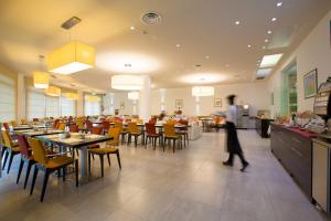 a person walking through a restaurant with tables and chairs at UNAWAY Cesena Nord in Cesena