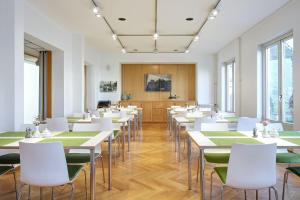 um quarto com mesas, cadeiras brancas e janelas em Gästehaus Lazarus em Berlim