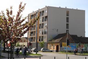 un edificio en una calle de la ciudad con gente montando bicicletas en Top Center en Osijek