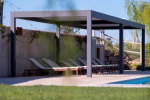 a pavilion with white chairs and a pool at Can Alemany in Santa Margarita de Mombúy