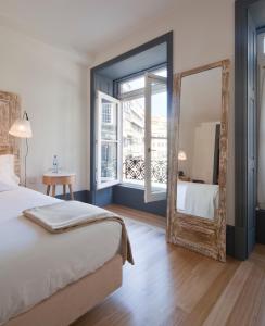 um quarto com um espelho, uma cama e uma janela em Porto A.S. 1829 Hotel no Porto
