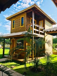 a wooden house with a palm tree in front of it at CHALES VILLAGE COR-PENINSULA DE MARAU-BAHIA in Barra Grande