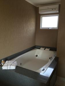 a bath room with a tub and a window at Hotel Fazenda Santa Maria in Serra Negra