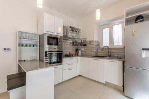 a kitchen with white cabinets and stainless steel appliances at Apartment DeLux in Split