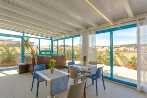 a room with tables and chairs and large windows at Hotel Trinacria in San Vito lo Capo