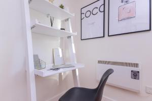 a black chair in a room with white shelves at Oxfordshire Living - The Alice Apartment - Oxford in Oxford