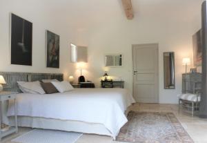 a white bedroom with a white bed and a chair at Les Terrasses - Gordes in Gordes