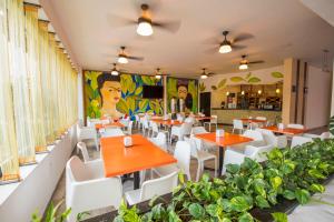 un restaurante con mesas de naranja y sillas blancas en Hotel Andiroba Palace, en Tuxtla Gutiérrez
