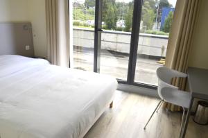 a bedroom with a bed and a desk and a large window at Le Grand Hotel in Maubeuge