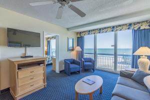 a living room with a couch and a tv and a balcony at Yachtsman Oceanfront Resort in Myrtle Beach