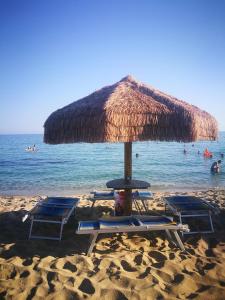 a straw umbrella and lounge chairs on a beach at Villa Mary in Torre Lapillo