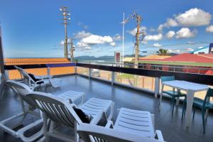 a balcony with white chairs and tables on a building at Cris Hotel in Florianópolis