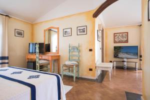 a bedroom with a bed and a desk and a television at Hotel Poseidonia in Àrbatax
