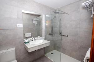 a bathroom with a shower, sink, and mirror at Hotel Complejo Los Rosales in Torremolinos