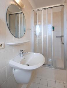 a white bathroom with a sink and a shower at Hotel Münchner Löwenbräu in Cuxhaven