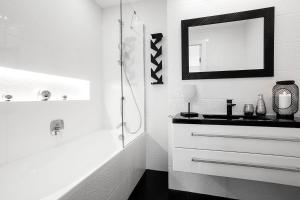 ein weißes Badezimmer mit einem Waschbecken und einem Spiegel in der Unterkunft VIU White Moon Apartment in Danzig