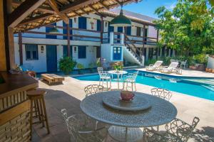 un patio con mesa, sillas y piscina en Pousada Sao Luiz, en Porto Seguro